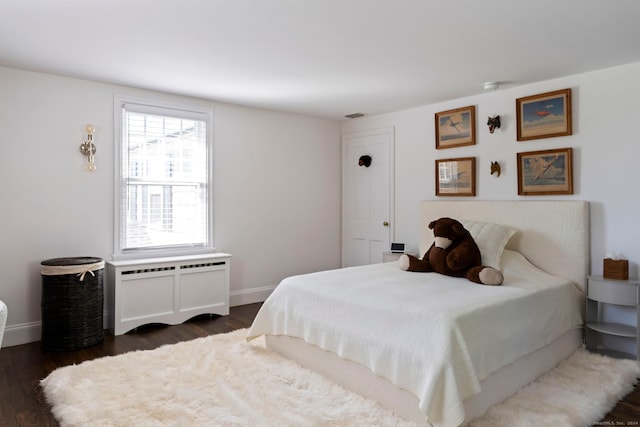 bedroom with dark hardwood / wood-style flooring and radiator heating unit