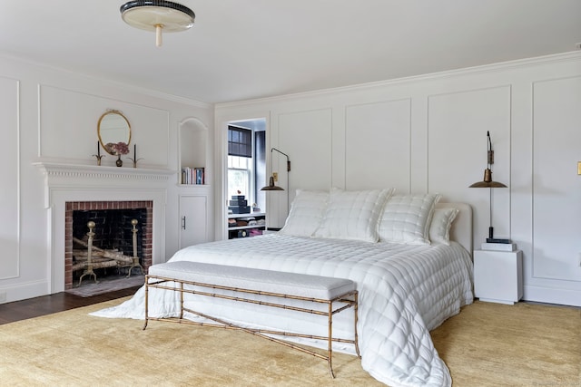 bedroom with crown molding, a brick fireplace, and hardwood / wood-style floors