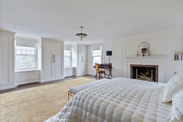 bedroom featuring light hardwood / wood-style floors, ornamental molding, multiple windows, and a fireplace