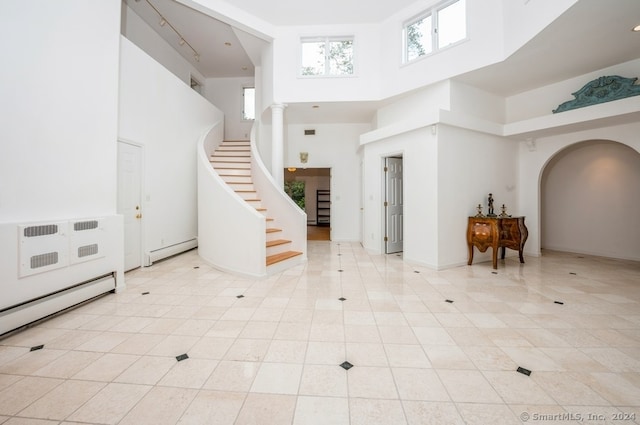 tiled entrance foyer featuring a baseboard radiator and a high ceiling