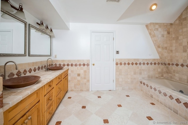 bathroom with tile walls, vanity, a bathing tub, and tile patterned floors