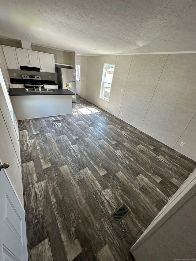 kitchen featuring a textured ceiling, stainless steel fridge, dark hardwood / wood-style flooring, sink, and white cabinets