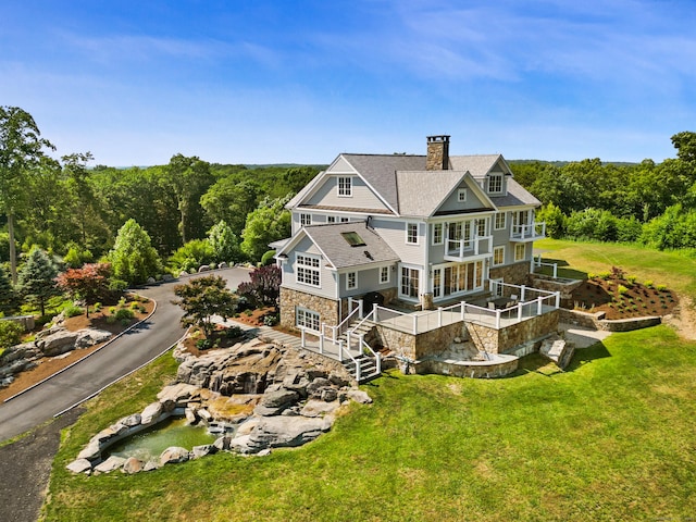 29 Rogues Rdg, Weston, CT 06883 - back of property with stone siding, a chimney, a yard, a shingled roof, and a balcony