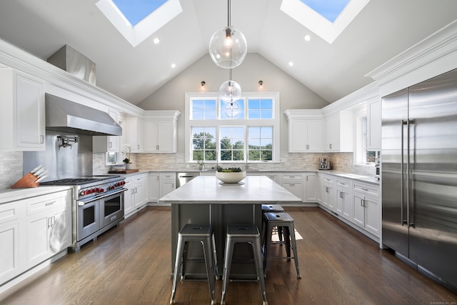 kitchen featuring high end appliances, wall chimney range hood, dark hardwood / wood-style floors, and high vaulted ceiling