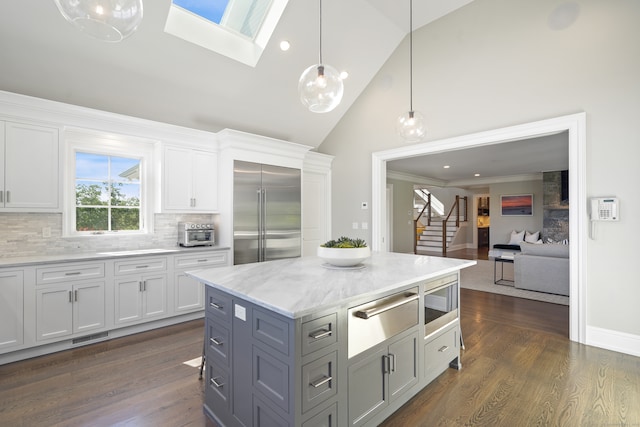 kitchen featuring dark hardwood / wood-style floors, hanging light fixtures, high vaulted ceiling, and built in appliances