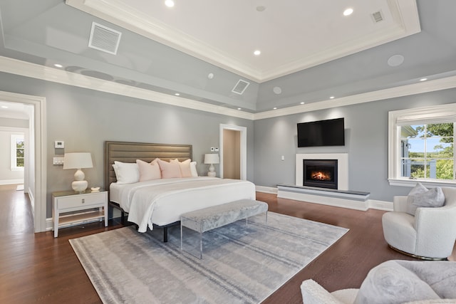 bedroom with ornamental molding, dark hardwood / wood-style floors, and a raised ceiling