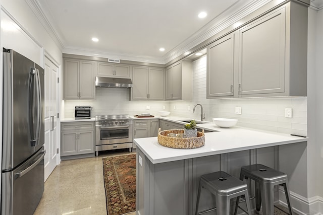 kitchen with kitchen peninsula, backsplash, a breakfast bar, gray cabinets, and stainless steel appliances