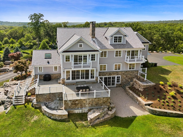 29 Rogues Rdg, Weston, CT 06883 - rear view of house with stone siding, a balcony, a chimney, and a patio