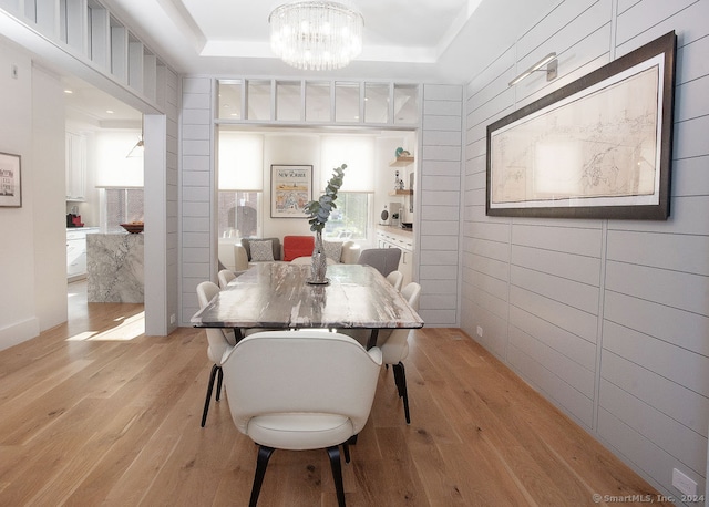 dining space with light hardwood / wood-style flooring, a chandelier, and a tray ceiling