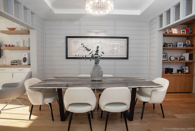 dining room with hardwood / wood-style floors, a tray ceiling, wooden walls, and a notable chandelier