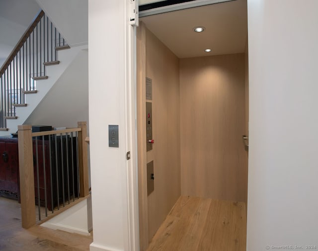 hall with elevator, a barn door, and light hardwood / wood-style floors