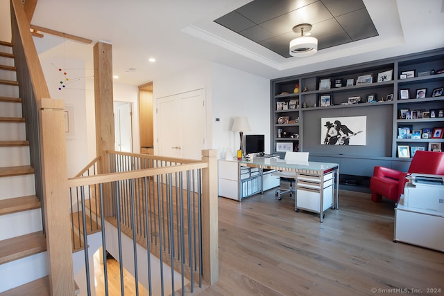 office space featuring a tray ceiling, built in features, and hardwood / wood-style floors