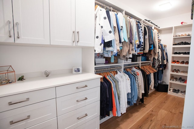 walk in closet with light hardwood / wood-style floors