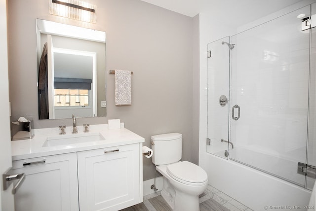 full bathroom with vanity, toilet, wood-type flooring, and enclosed tub / shower combo