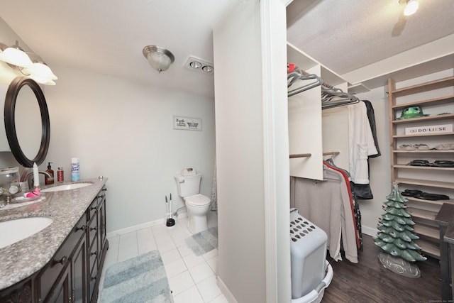 bathroom with a textured ceiling, toilet, tile patterned floors, and vanity