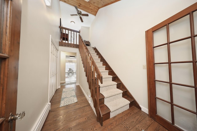 stairway with ceiling fan, hardwood / wood-style floors, wooden ceiling, high vaulted ceiling, and a baseboard radiator