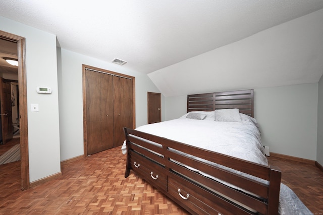 bedroom with light parquet floors, a closet, and lofted ceiling