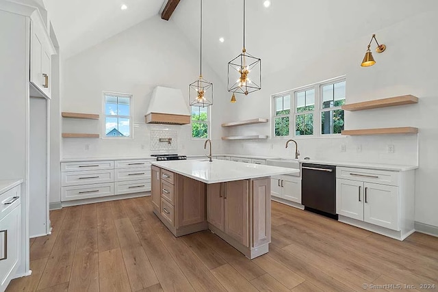 kitchen featuring custom range hood, white cabinetry, dishwasher, light wood-type flooring, and a kitchen island with sink