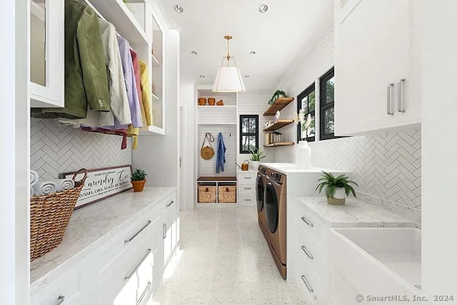 kitchen featuring pendant lighting, washer and dryer, light stone counters, and white cabinets