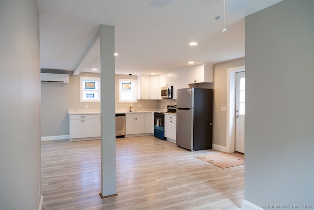 kitchen with light hardwood / wood-style floors, stainless steel appliances, sink, an AC wall unit, and white cabinetry