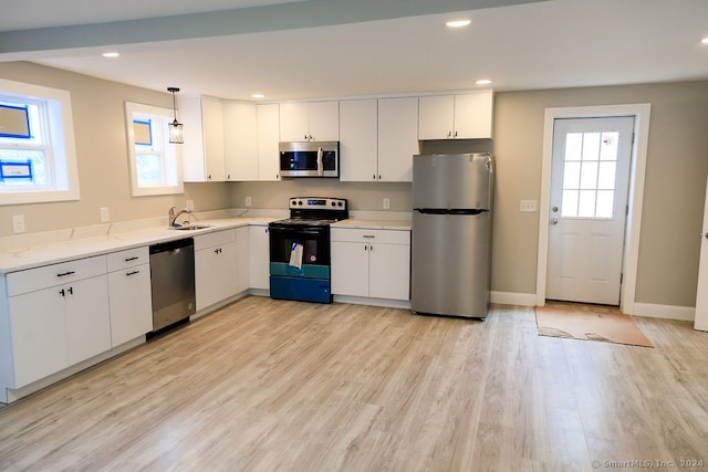 kitchen featuring appliances with stainless steel finishes, light hardwood / wood-style flooring, sink, and pendant lighting