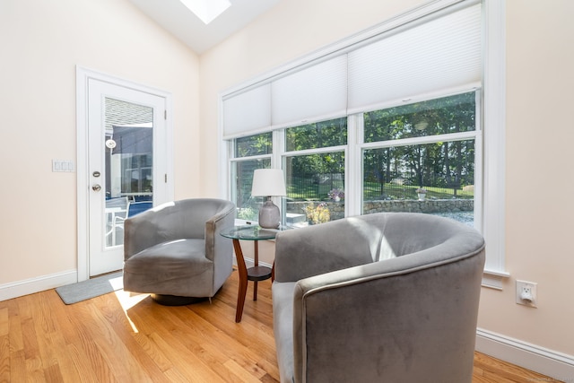 sitting room featuring wood-type flooring and vaulted ceiling with skylight