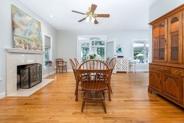 dining area featuring ceiling fan, a high end fireplace, and light wood-type flooring