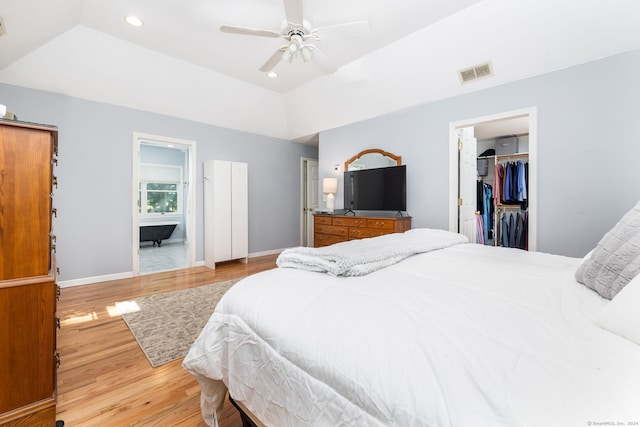 bedroom with hardwood / wood-style floors, a raised ceiling, a walk in closet, ceiling fan, and a closet