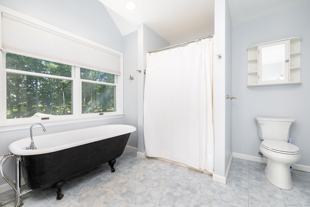 bathroom featuring a tub to relax in, vaulted ceiling, and toilet