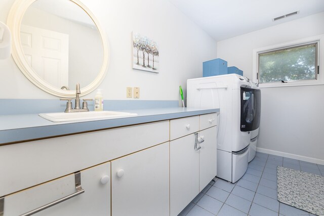 laundry area with light tile patterned flooring, cabinets, sink, and washer / dryer