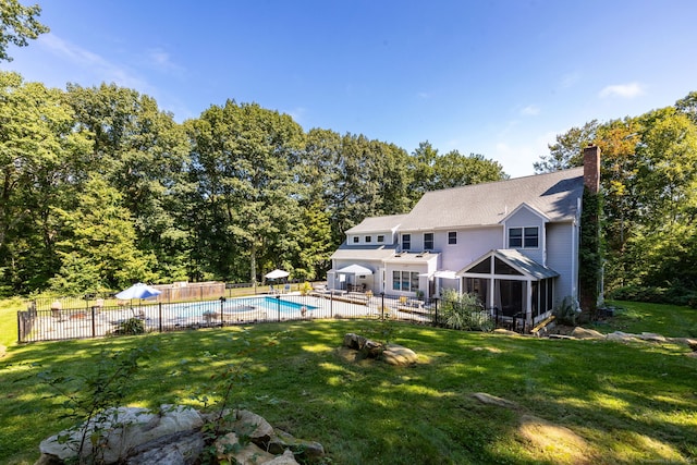 back of house featuring a sunroom, a fenced in pool, a yard, and a patio