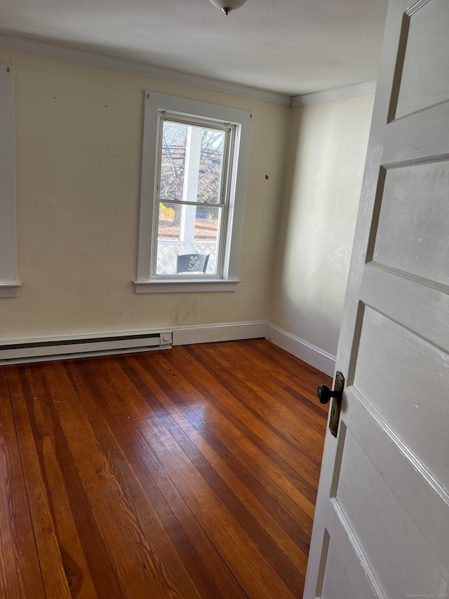 empty room with a baseboard heating unit, a barn door, and hardwood / wood-style floors