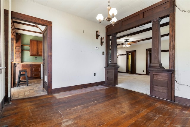 empty room featuring ceiling fan with notable chandelier, dark hardwood / wood-style flooring, and ornate columns