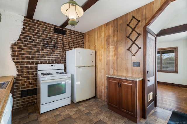 kitchen featuring dark wood-type flooring, white appliances, beam ceiling, and brick wall