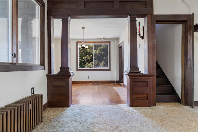 interior space with an inviting chandelier, radiator, and decorative columns