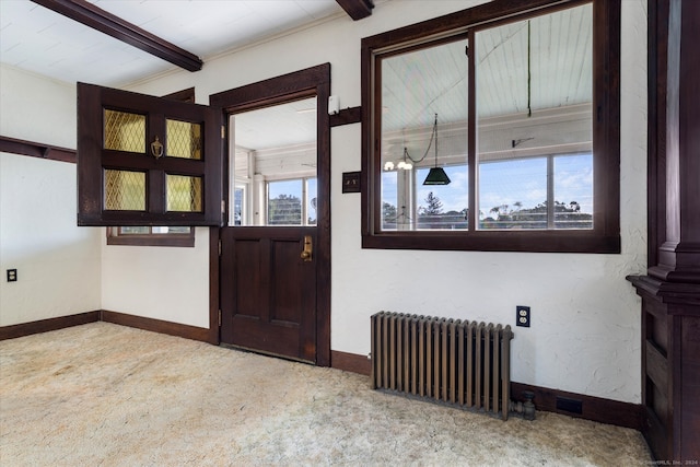 entryway with crown molding, radiator, an inviting chandelier, and carpet