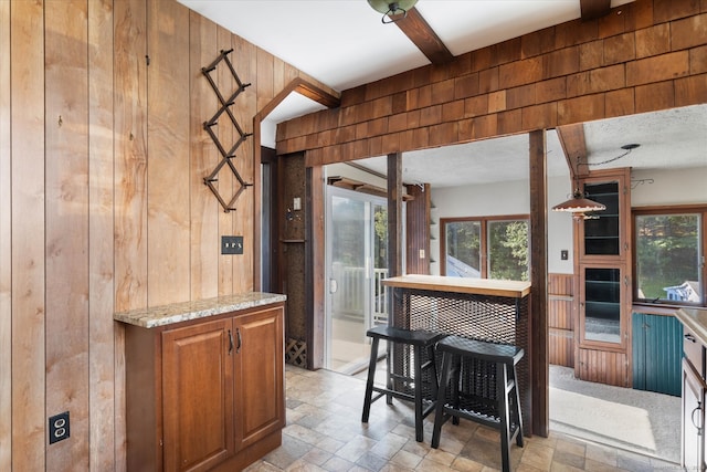 kitchen with a textured ceiling, wood walls, and light stone counters