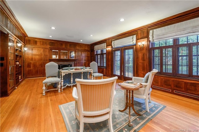 interior space with light wood-type flooring, wooden walls, and ornamental molding