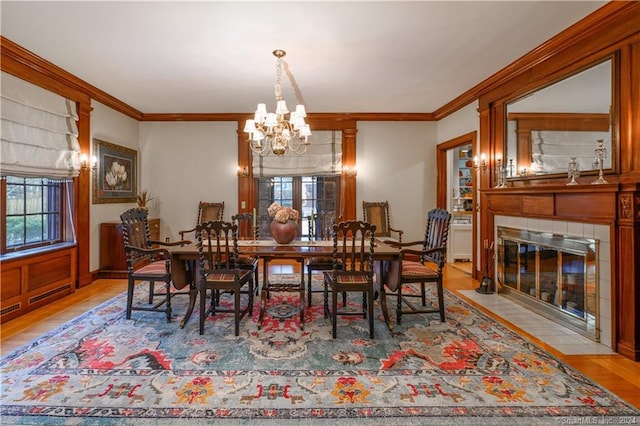 dining room featuring light hardwood / wood-style floors, a tile fireplace, a wealth of natural light, and an inviting chandelier