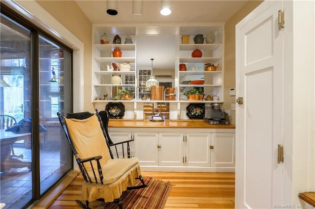 living area with built in features and light hardwood / wood-style flooring