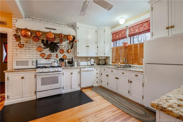 kitchen featuring white cabinetry, white appliances, light stone counters, and sink