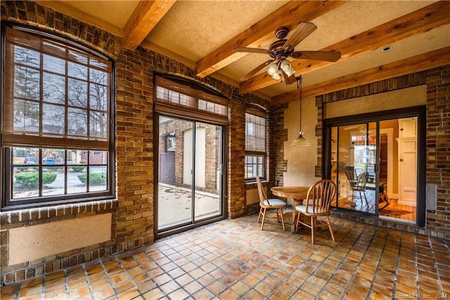 unfurnished sunroom with ceiling fan and beam ceiling