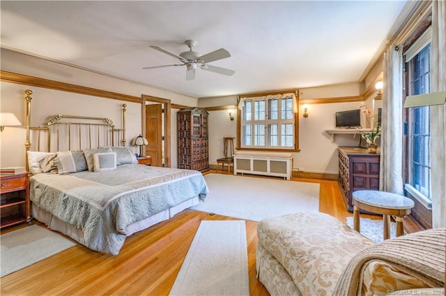 bedroom featuring ceiling fan, radiator heating unit, and wood-type flooring