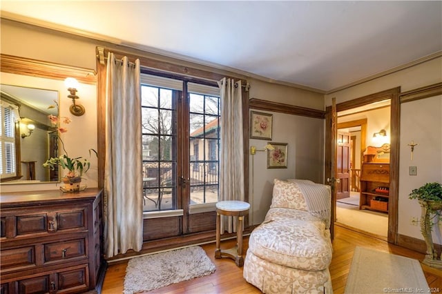 living area with crown molding and light hardwood / wood-style flooring