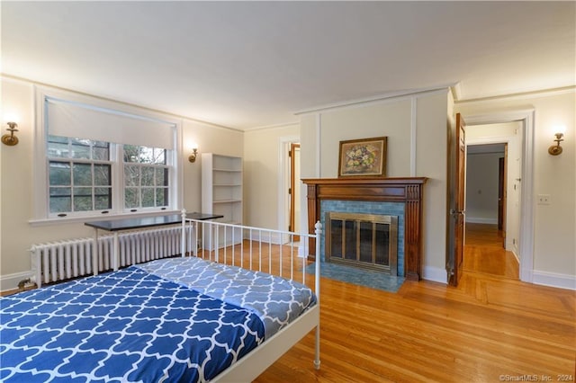 bedroom with light hardwood / wood-style floors, radiator heating unit, and ornamental molding