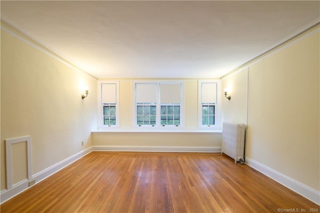 unfurnished room with crown molding, radiator, and wood-type flooring