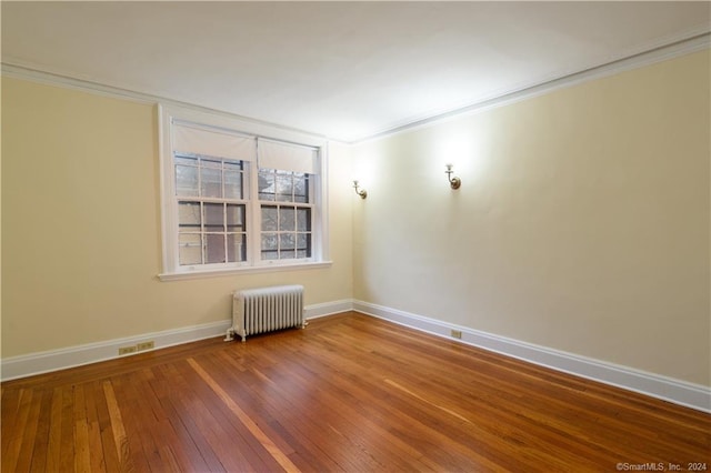 spare room with radiator heating unit, crown molding, and wood-type flooring