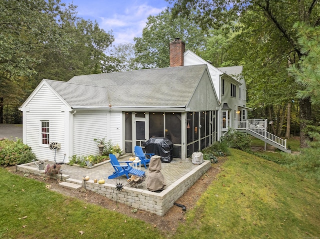 rear view of house with a sunroom, a yard, and a patio area