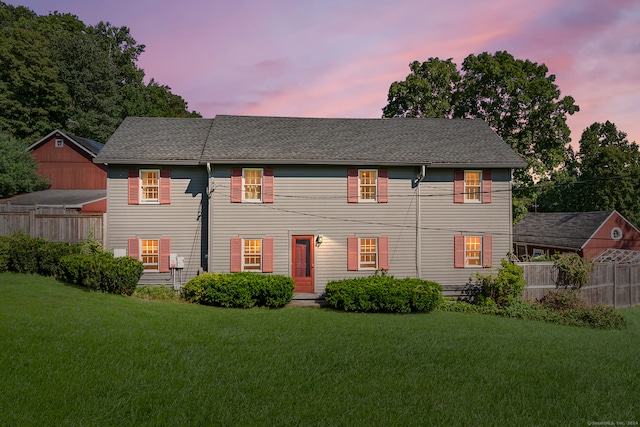 back house at dusk with a lawn