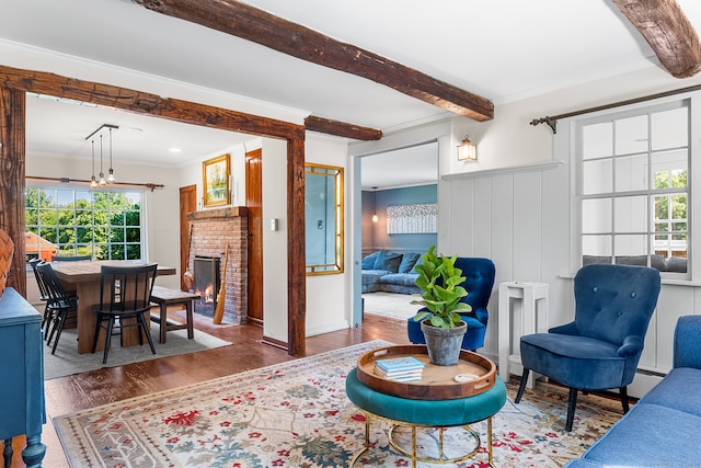 living room with ornamental molding, beamed ceiling, a fireplace, and dark hardwood / wood-style flooring